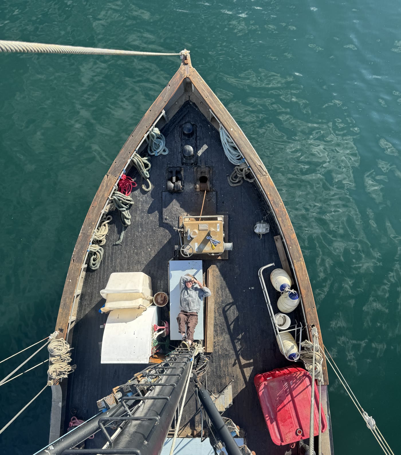 Overhead of Crane’s wooden bow, coils of line, a person on deck looking up