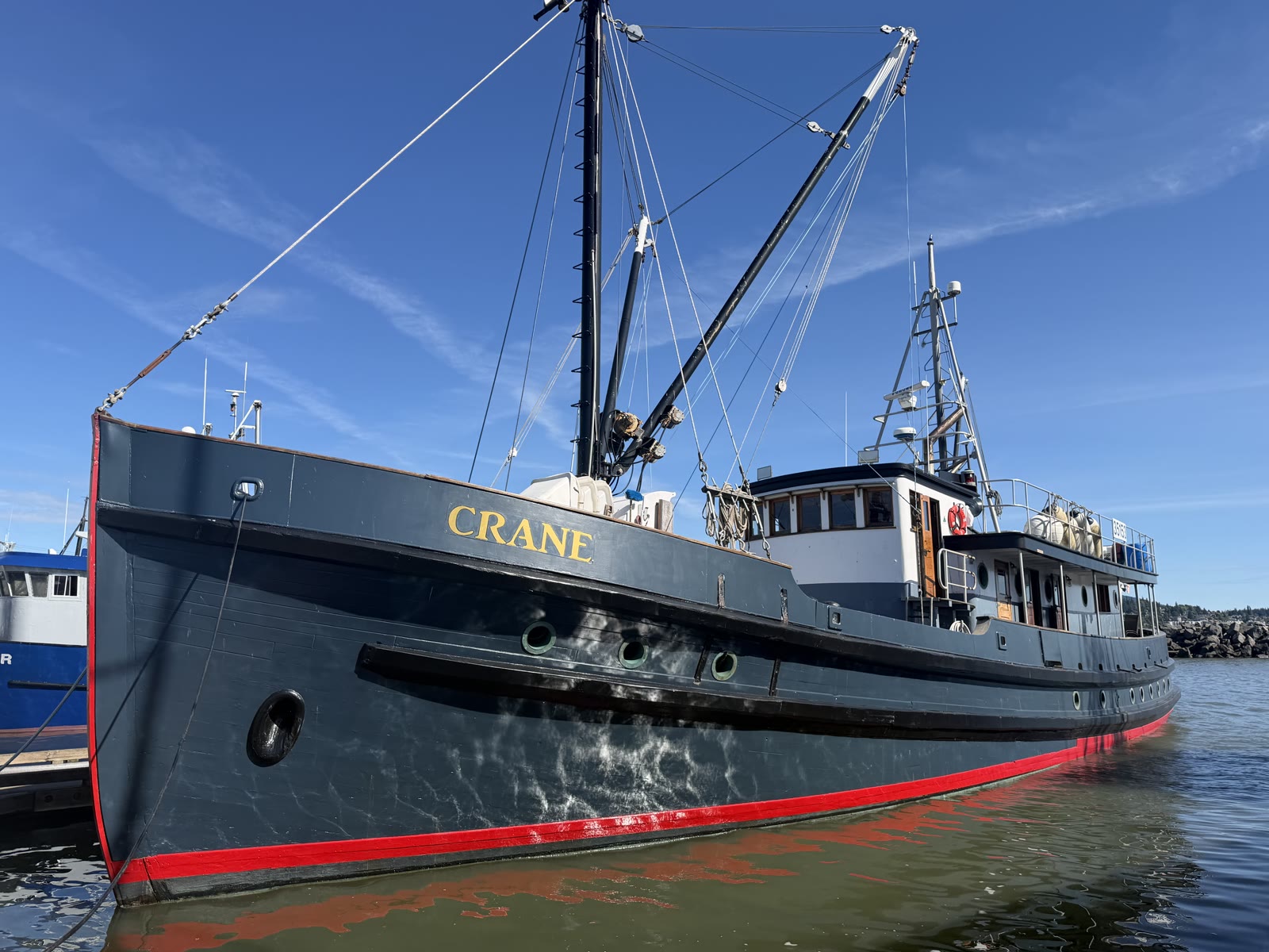 Crane at the dock: navy hull, gold CRANE on the bow, red boot stripe, white house