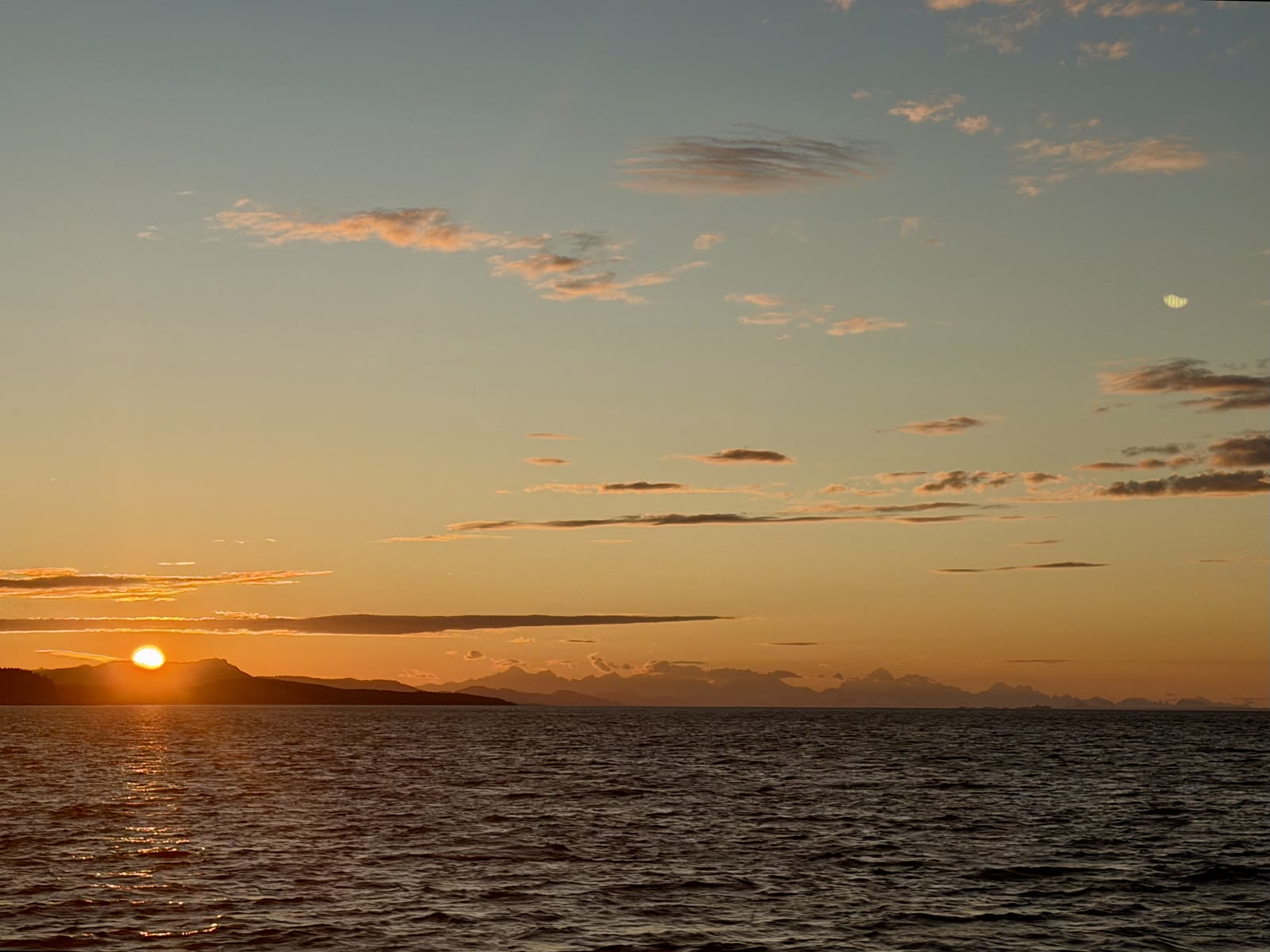 Sunset over water, mountains in silhouette